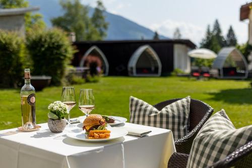 a table with a plate of food and two glasses of wine at Soldanella by Hotel Adula in Flims