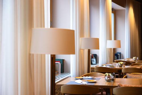 a dining room with tables and chairs with lamps at Soldanella by Hotel Adula in Flims