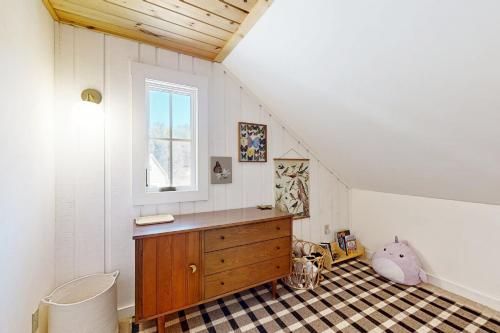 a attic room with a wooden dresser and a window at Heart Of The Mountains in Thornton