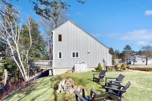 a large white barn with chairs on the lawn at Heart Of The Mountains in Thornton