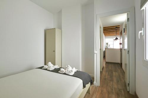 a bedroom with a white bed and a hallway at Ol Cute apartment in quiet Olivera st in Barcelona