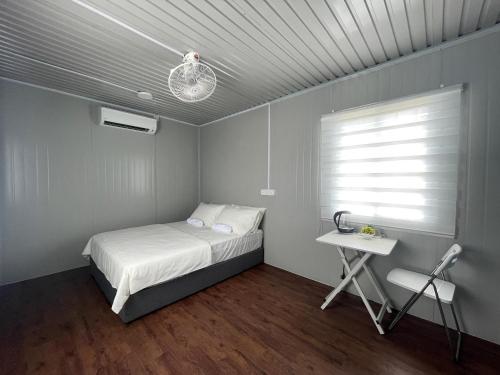 Schlafzimmer mit einem Bett, einem Tisch und einem Fenster in der Unterkunft Country Road Homestay in Simpang Empat