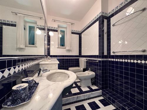 a blue tiled bathroom with a sink and a toilet at Villa Doria 16 Pax by VILLASRETREATS in Portovenere