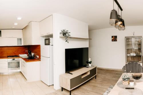 a kitchen with a large flat screen tv on a white wall at Mano jūra in Palanga