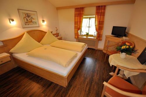 um quarto de hotel com uma cama e uma televisão em Brandstätter Hof em Ruhpolding