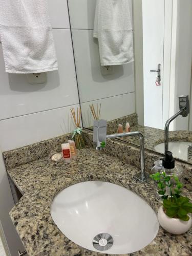a bathroom counter with a white sink and a mirror at Loft Central in Passo Fundo