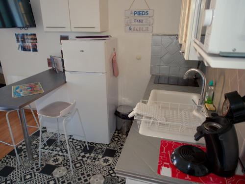 une petite cuisine avec un évier et un réfrigérateur dans l'établissement Escale au Sud, un appart les pieds dans l eau :), au Barcarès