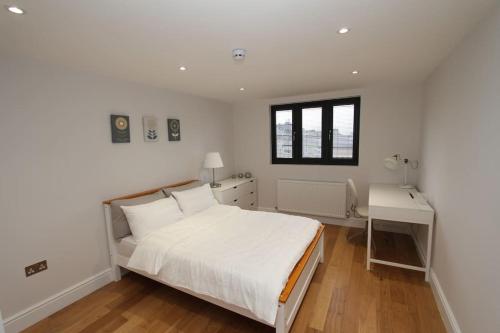 a white bedroom with a bed and a desk at Amazing Loft One Bedroom Apartment - E17 Village in London