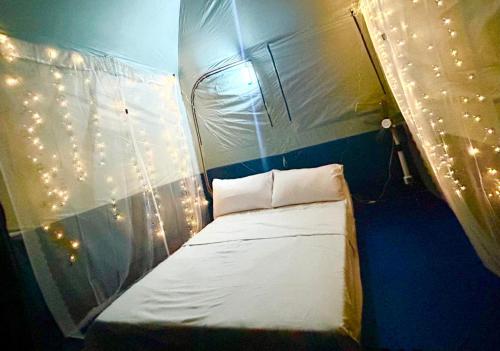 Una cama pequeña en una tienda con luces. en Stargazing tent in Balcony at EKG House Rental, en Manila