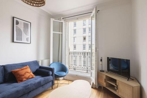 un salon avec un canapé bleu et une télévision dans l'établissement Apartment 1 Bedroom # Paris 14 # Alesia, à Paris