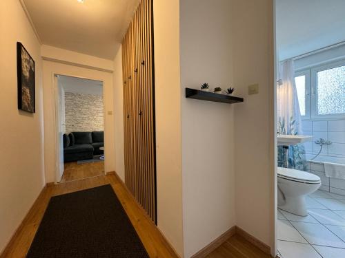 a hallway with a bathroom with a toilet and a couch at Zentrales 2-Zi Apartment by Rabe - Kirche - Coffee-Bar in Karlsruhe
