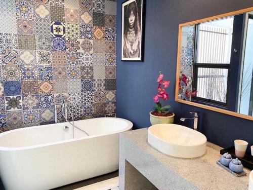 baño con bañera y pared de azulejos en พูลวิลล่ากรุงเทพ en Bangna