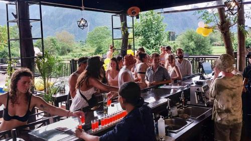 a group of people standing around a bar at Mad Monkey Vang Vieng in Vang Vieng