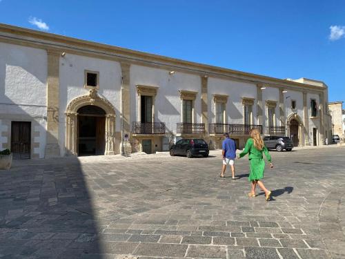 a woman in a green dress walking in front of a building at Palazzo Giustiniani L'Ambasciatore in Sogliano Cavour