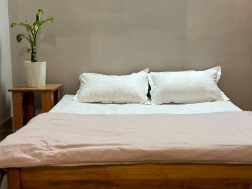 uma cama com lençóis e almofadas brancos e uma planta em Shyama tara em Panchanai