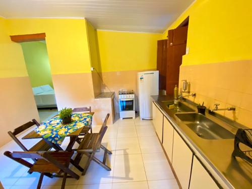 a kitchen with a table and a sink and a refrigerator at Pousada Jardim Lençóis in Lençóis