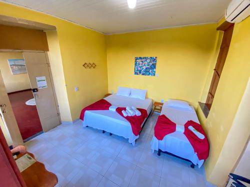 two beds in a room with yellow walls at Pousada Jardim Lençóis in Lençóis