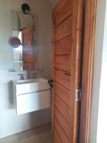 a bathroom with a wooden door and a sink at Mirada al Champaqui - Departamento de Montaña in Villa Yacanto