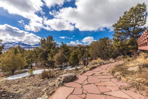 a brick path with trees and mountains in the background at Catamount Lodge in Ridgway