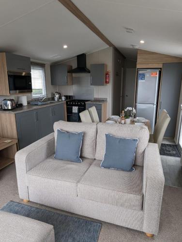 a living room with a couch and a kitchen at Stylish Modern Bright Caravan with Views sleeps 6 Littlesea Haven Weymouth in Weymouth