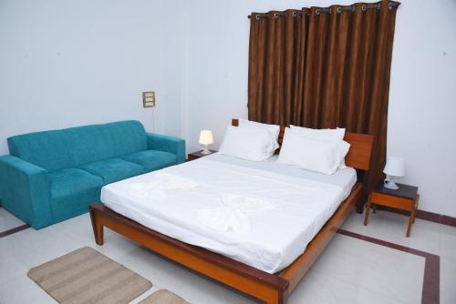 1 dormitorio con 1 cama y 1 sofá azul en Hotel Solis Stay en Solapur