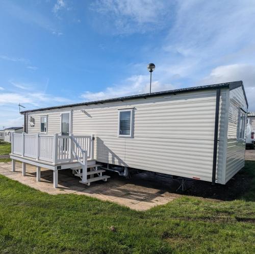 a large white trailer with a porch and a house at Stylish Modern Bright Caravan with Views sleeps 6 Littlesea Haven Weymouth in Weymouth
