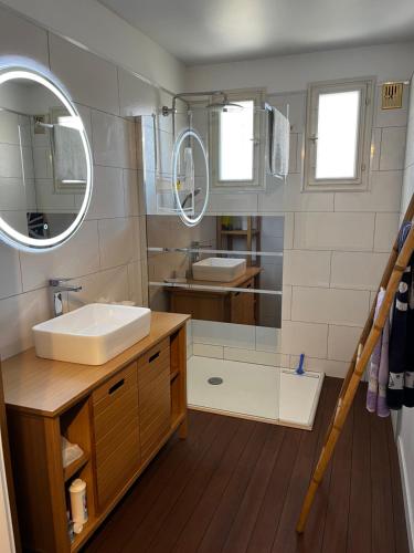 une salle de bain avec un lavabo et un miroir dans l'établissement La Maison Brennus , Piscine, 15 Min des Plages, à Béziers