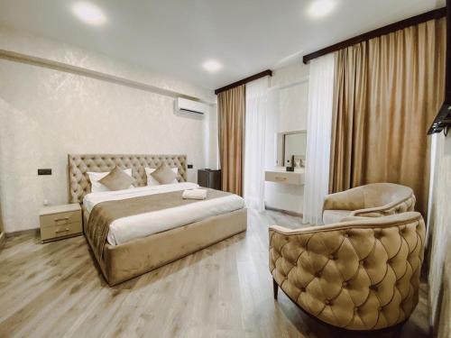 Royal Renaissance Hotel في يريفان: غرفة نوم بسرير كبير وكرسي