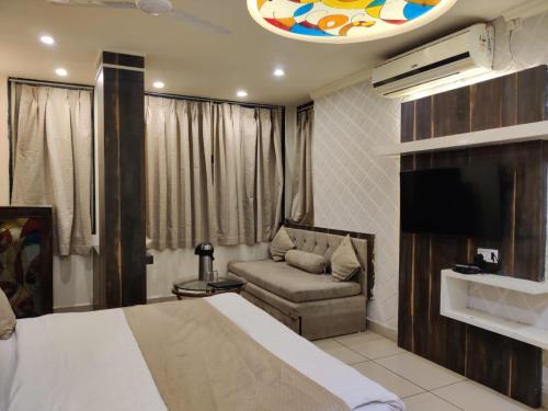 a bedroom with a bed and a couch and a tv at Abhilasha hotel pachmarhi` in Pachmarhī