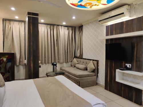 1 dormitorio con cama, sofá y TV en Abhilasha hotel pachmarhi`, en Pachmarhī