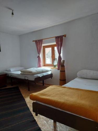 1 dormitorio con 2 camas y ventana en Kuća za odmor Vučipolje, en Tomislavgrad