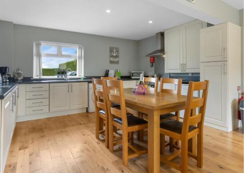 cocina con mesa de madera y algunas sillas en Benone Getaways, en Derry Londonderry