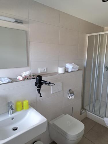 a bathroom with a toilet and a sink and a shower at Pension am Park in Rust