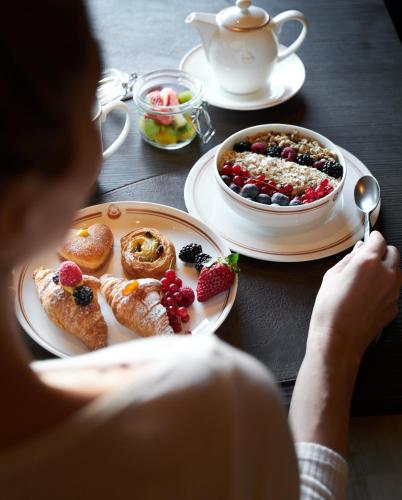 Una donna seduta a un tavolo con piatti di cibo di Rosapetra SPA Resort - Small Luxury Hotels of the World a Cortina dʼAmpezzo