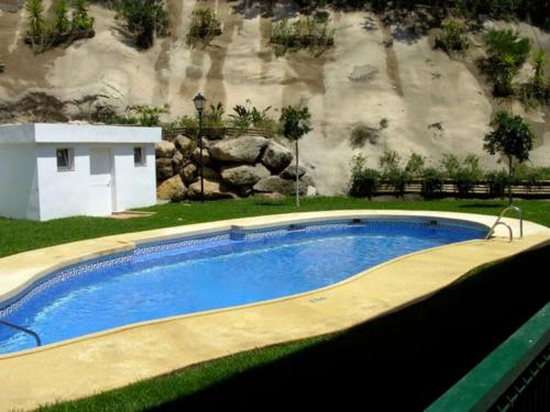 a large swimming pool in front of a rock wall at Acogedor apartamento con vistas al Mediterráneo. in Mojácar