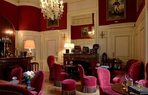 een kamer met rode stoelen en tafels en een kroonluchter bij Chateau Colbert in Maulévrier