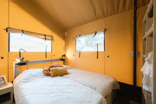 Cama en habitación con paredes y ventanas de color amarillo en Safaritent en Ingen