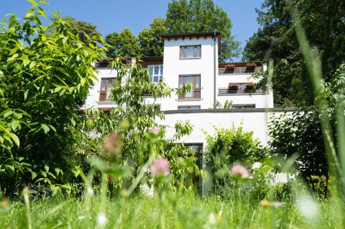 a white building behind a field of grass at Hotel Suggenbad in Waldkirch