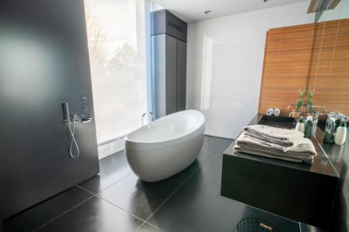 Bed & Wellness Boxtel, luxe kamer met airco en eigen badkamer, ligbad في بوكستيل: حمام مع حوض أبيض يجلس على أرضية سوداء