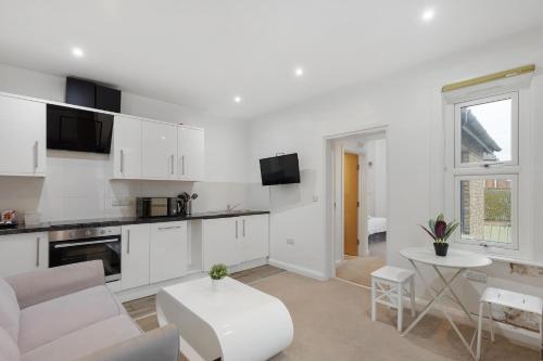 a kitchen with white cabinets and a table in a room at Central and Modern One Bedroom Flat 201 in Oxford