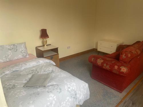 um quarto com uma cama e uma cadeira vermelha em Kickham Street Budget Accommodation em Carrick-on-Suir