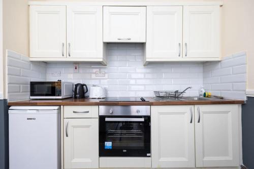 cocina blanca con armarios blancos y microondas en Homely 1 bedroom apartment in Smithfield, Dublin, en Dublín