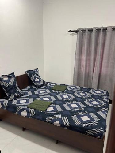 a bedroom with a bed with a blue and white comforter at Augustin Guest House in Point Pedro