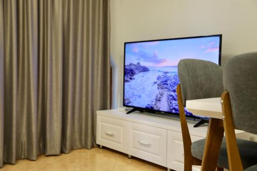 een flatscreen-tv op de top van een witte kast bij Sea View Apartments - The Suite in Durrës
