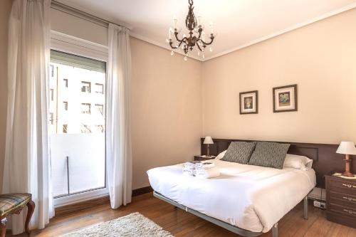 1 dormitorio con 1 cama con lámpara de araña y ventana en Horia apartment by People Rentals, en Bilbao