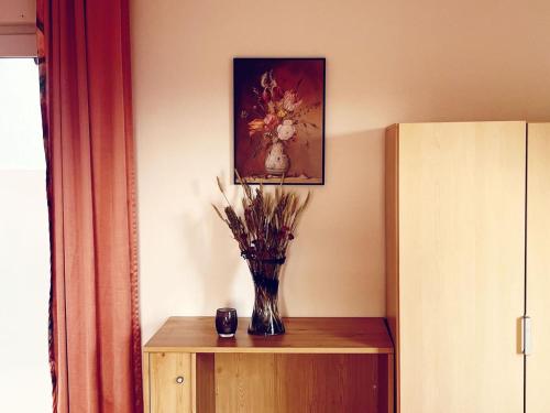 a vase of flowers on a table with a painting at Ferienwohnung mit WINTERGARTEN in Bahnhofsnähe in Eystrup