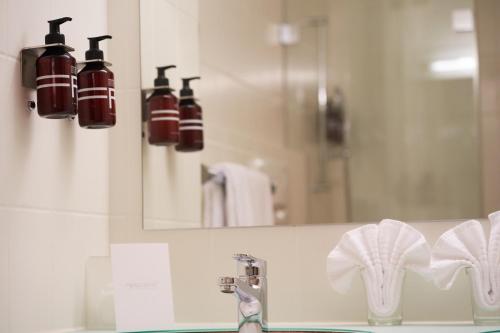 W łazience znajduje się umywalka, lustro i umywalka. w obiekcie Soldanella by Hotel Adula w mieście Flims