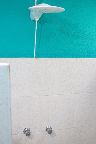 a bathroom with a white tiled wall and a light at pousada da sarafina ltda in Salvador