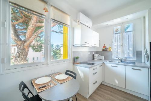 une cuisine avec des armoires blanches et une table avec des chaises dans l'établissement Petit Bonheur - Appt climatisé proche de la mer, à Argelès-sur-Mer