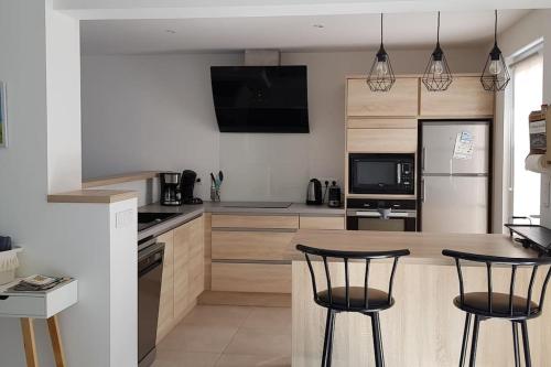 une cuisine avec deux tabourets de bar et un comptoir dans l'établissement Maison avec terrasse Classée 3*, à La Brée-les-Bains